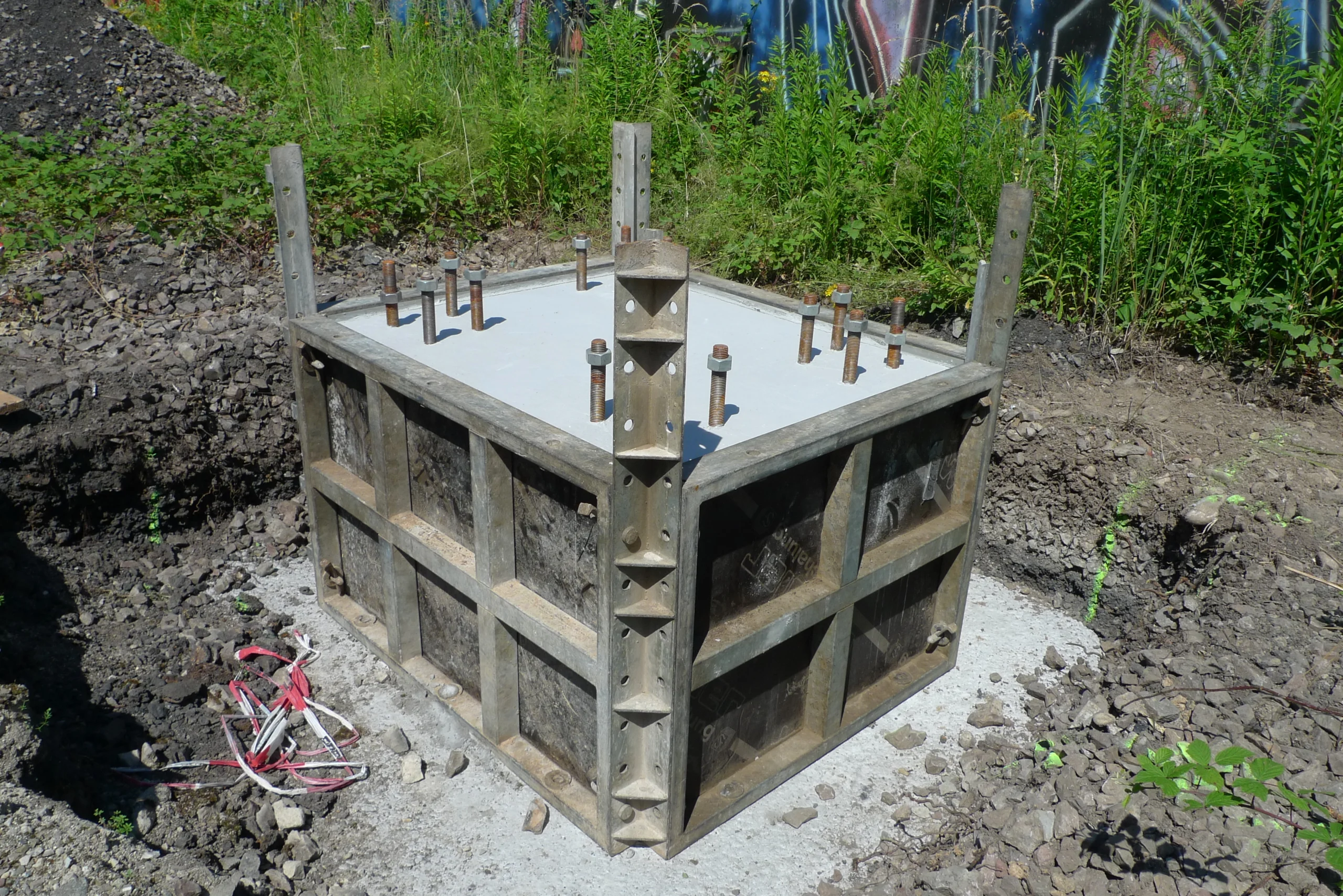 DELTA-Schalung in einer Grube neben einem frisch betonierten Fundament mit Ankerbolzen