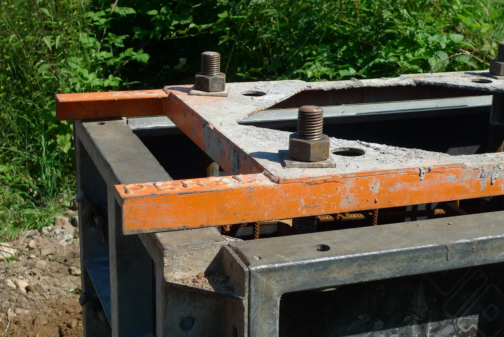 DELTA-Schalung mit orangefarbenem Rahmen und Ankerbolzen über einem Fundament