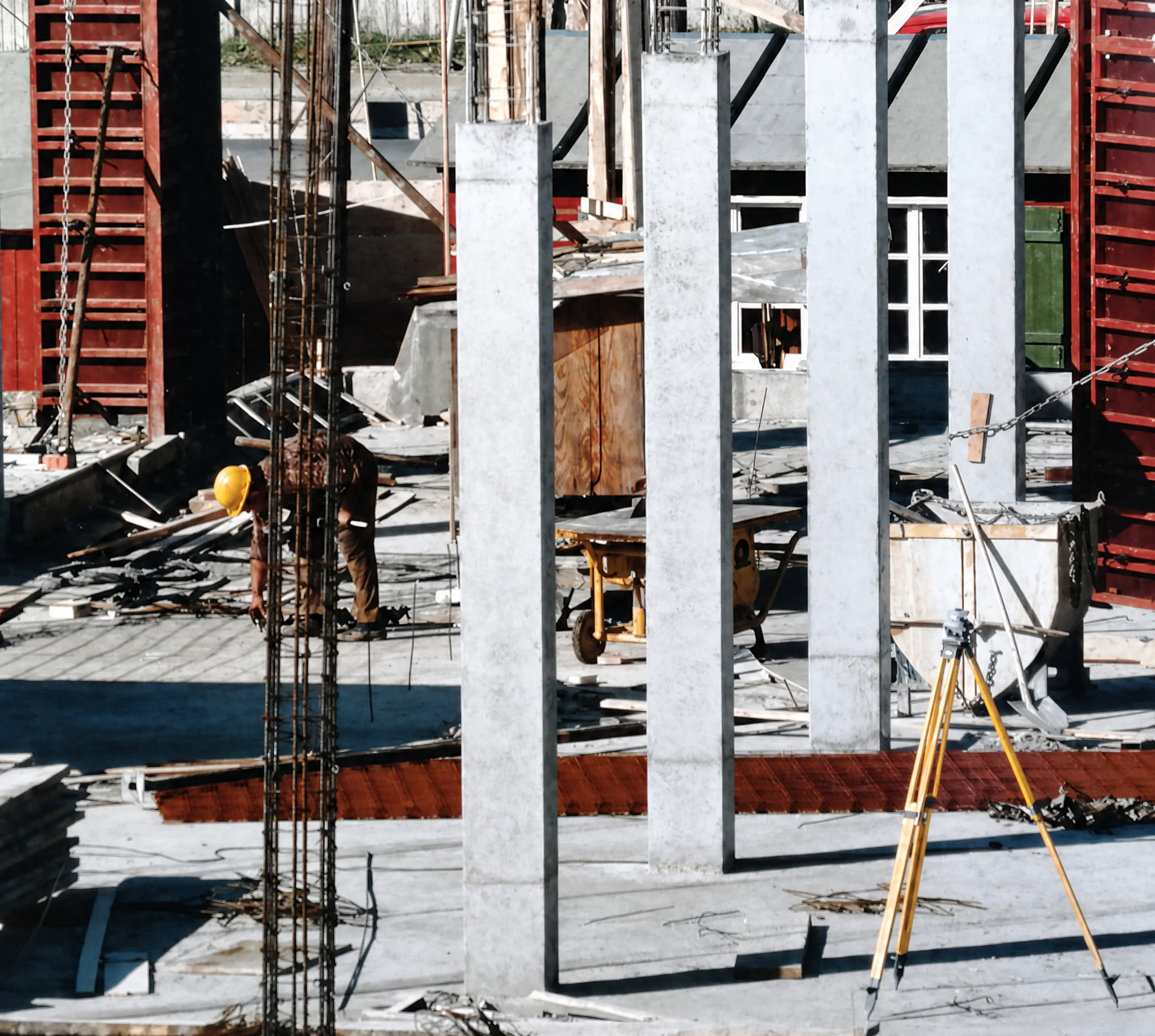 Frisch betonierte Säulen auf einer Baustelle, rot lackierte Säulenschalungen am Rand